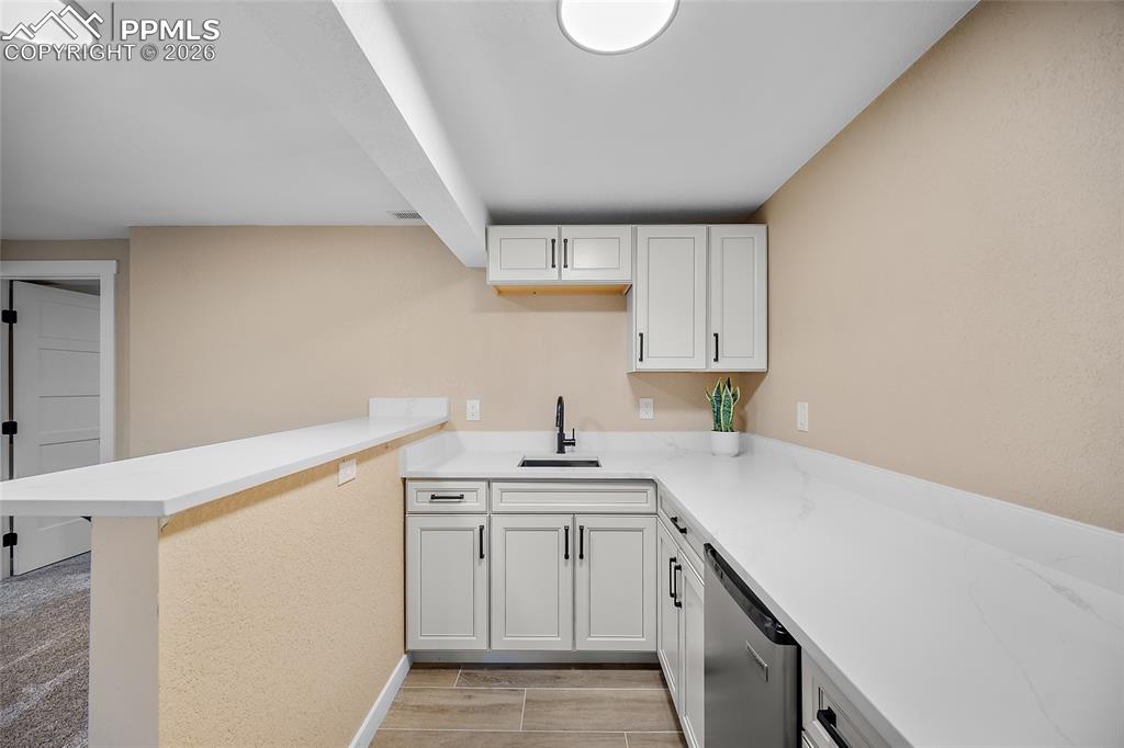 Wet bar with a peninsula, white cabinetry and fridge
