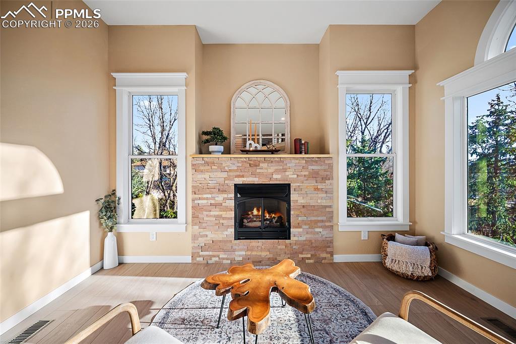 Living area featuring bright natural light, LVP flooring, a high ceiling, and fire place