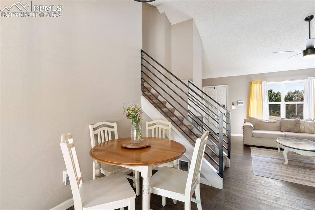 Dining area with stairs, wood finished floors, ceiling fan, and high vaulted ceiling