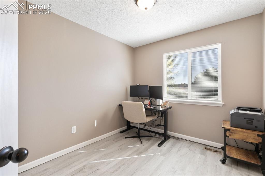 Home office featuring a textured ceiling and light wood-type flooring