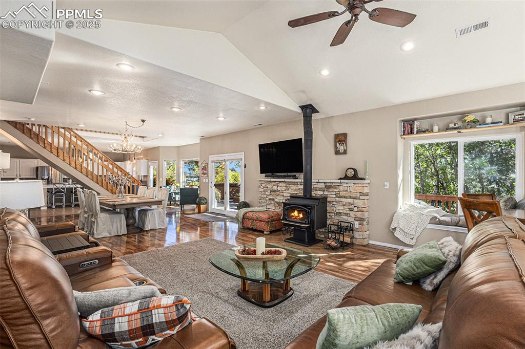 Living room with a wood stove, wood finished floors, high vaulted ceiling, recessed lighting, and a ceiling fan