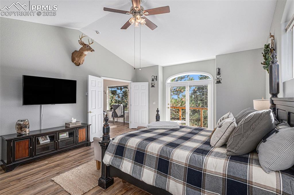 Bedroom featuring access to outside, vaulted ceiling, dark wood-style floors, and a ceiling fan