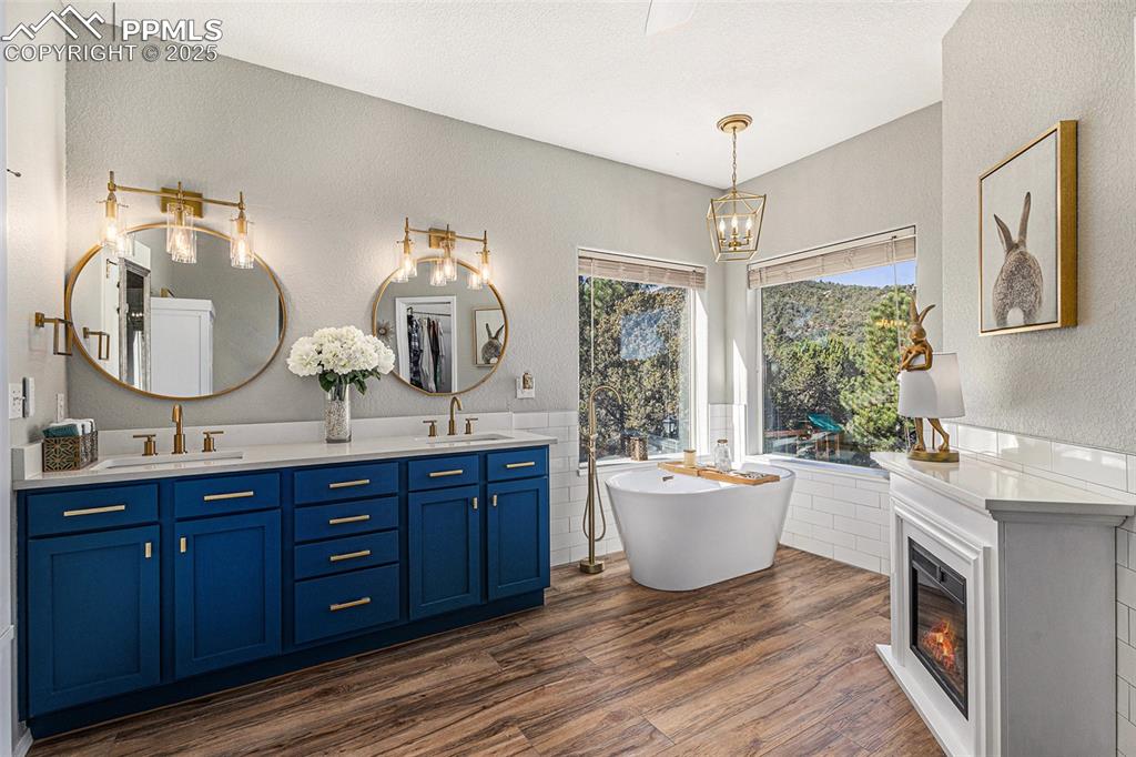 Ensuite bathroom with double vanity, dark wood finished floors, a shower stall, and ceiling fan