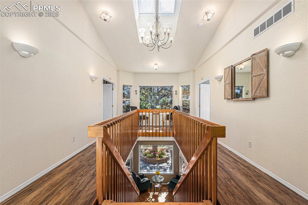 Stairs featuring lofted ceiling, a chandelier, and wood finished floors