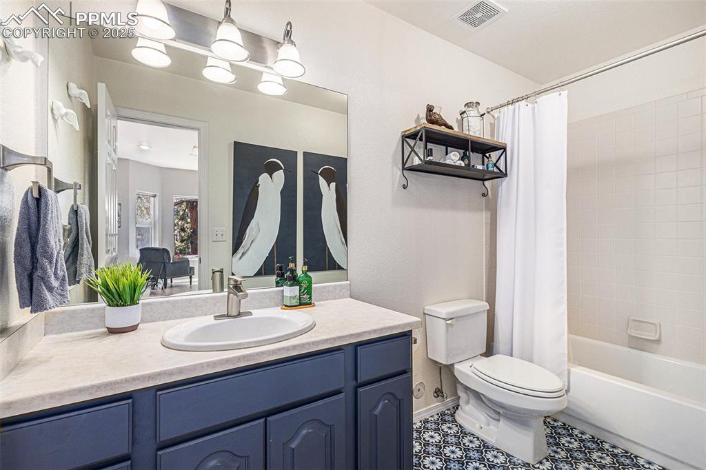 Full bathroom with vanity, a textured wall, and a shower with curtain