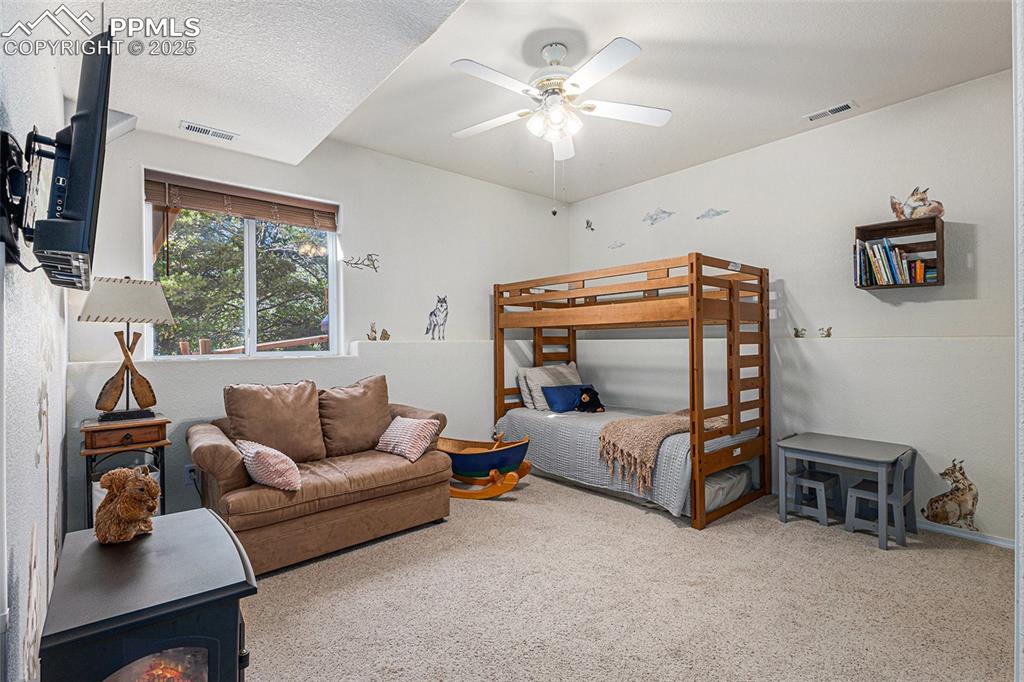 Bedroom featuring a wood stove, light colored carpet, a closet, and a textured wall