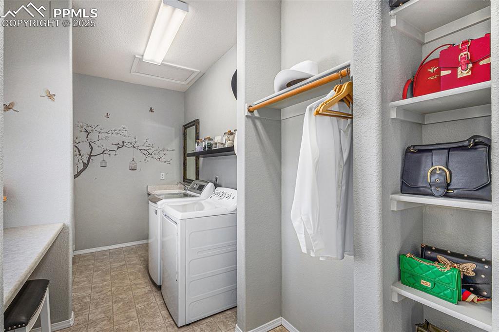 Laundry room with independent washer and dryer, vaulted ceiling, and attic access