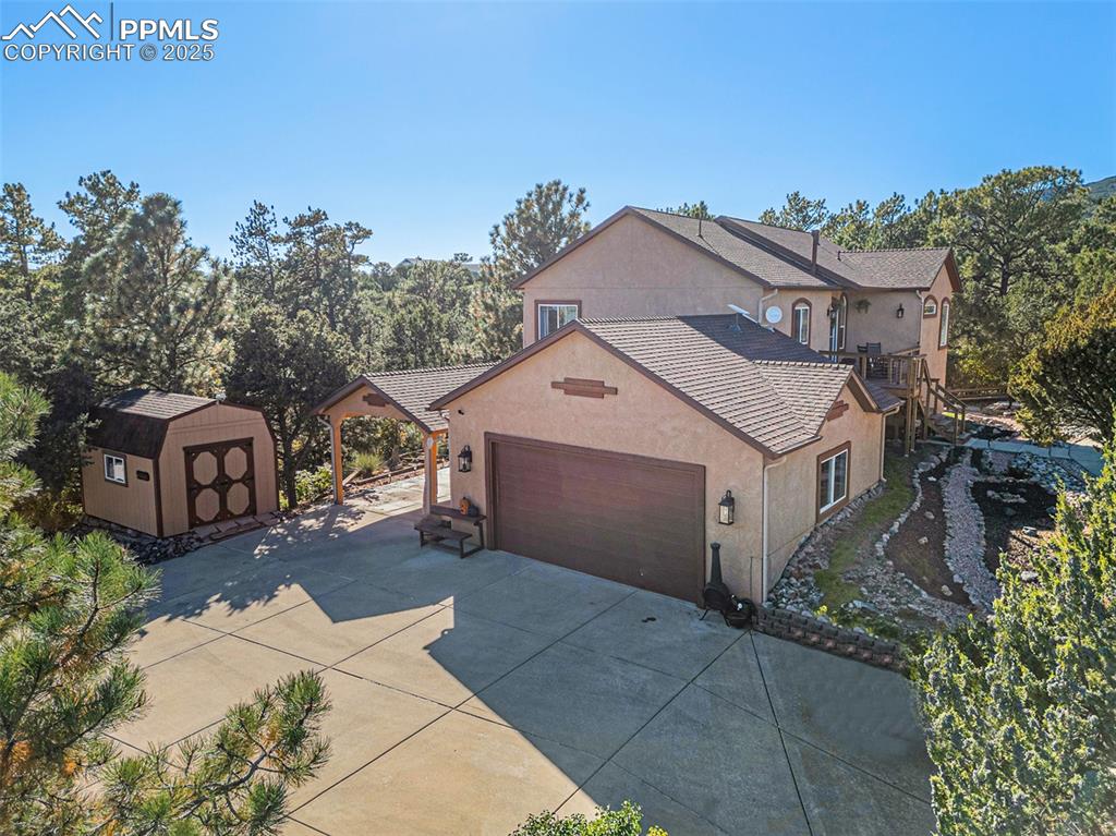 View of property exterior featuring a storage unit, stucco siding, driveway, and an attached garage