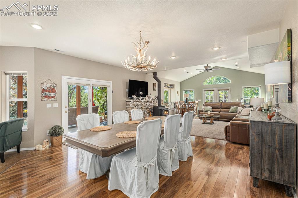 Living room featuring a wood stove, lofted ceiling, plenty of natural light, stairs, and a ceiling fan