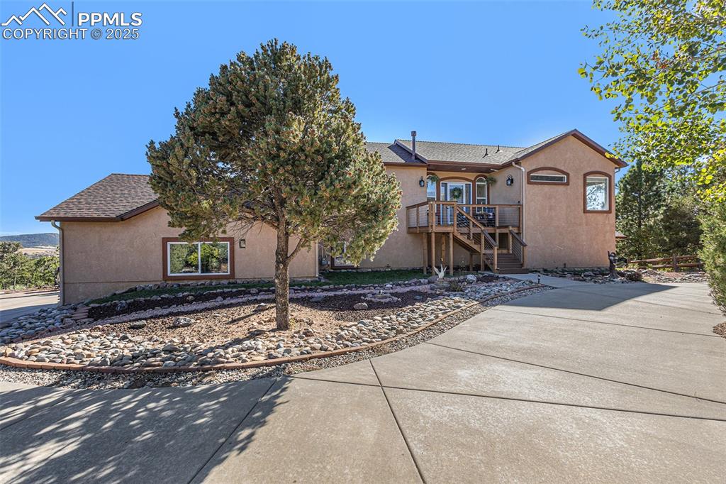 View of front facade featuring stucco siding, a wooden deck, stairway, and roof with shingles