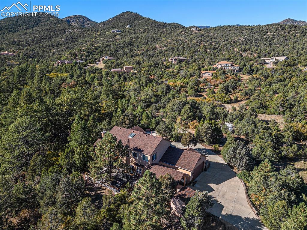 Aerial view of property's location with a heavily wooded area and a mountainous background