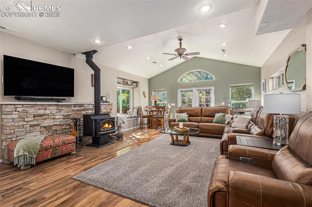 Dining space with dark wood-style flooring, vaulted ceiling, a wood stove, recessed lighting, and a chandelier