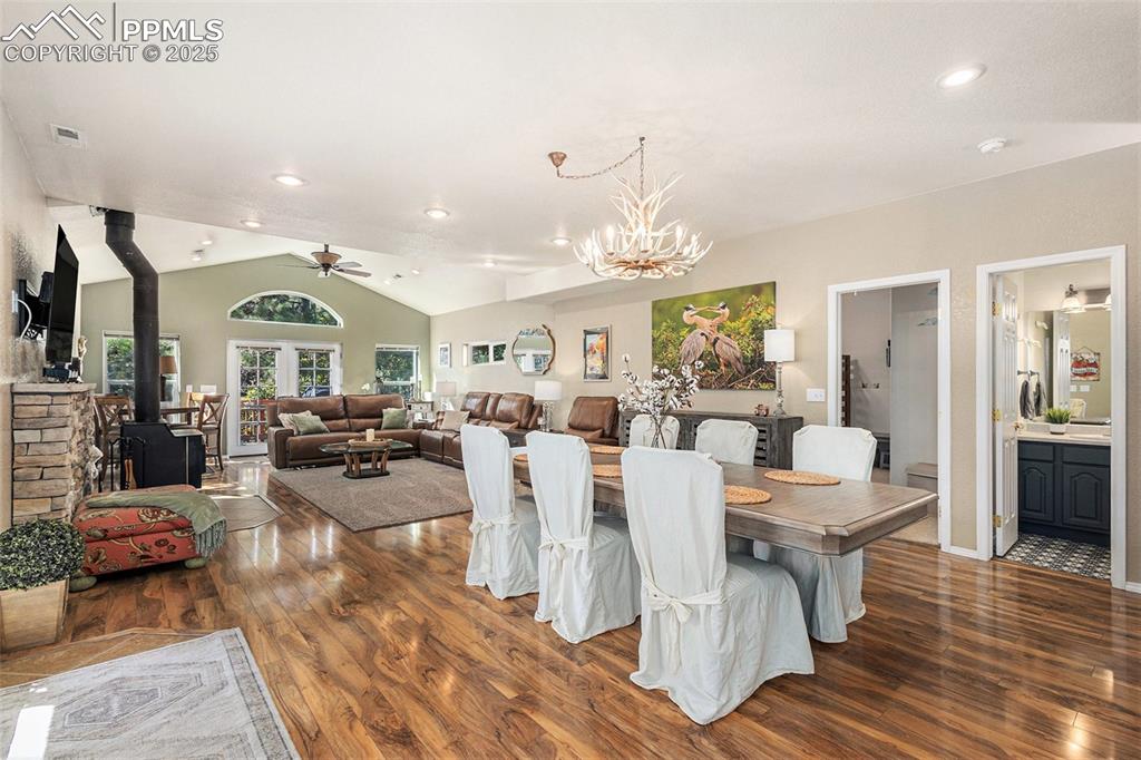 Dining area with a wood stove, healthy amount of natural light, dark wood-type flooring, lofted ceiling, and recessed lighting