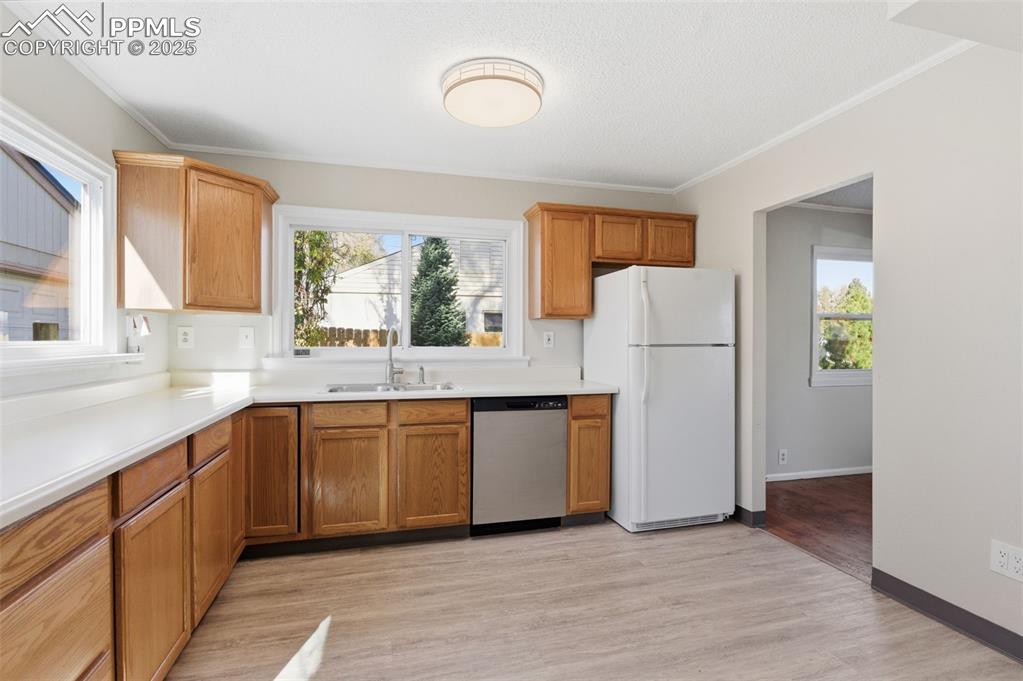 Kitchen with freestanding refrigerator,  light countertops, stainless steel dishwasher, 