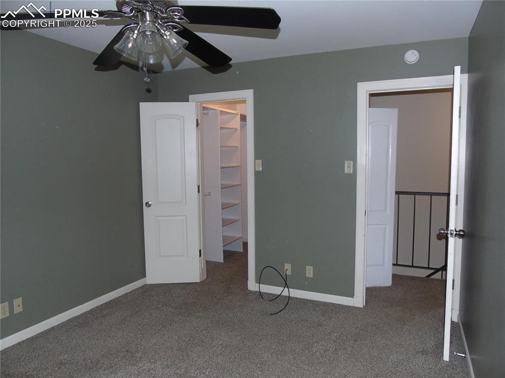 Unfurnished bedroom with carpet flooring, a walk in closet, and a ceiling fan