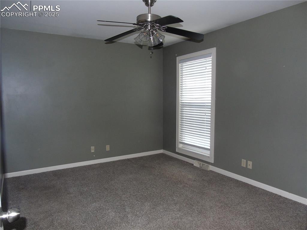 Spare room with dark carpet and a ceiling fan