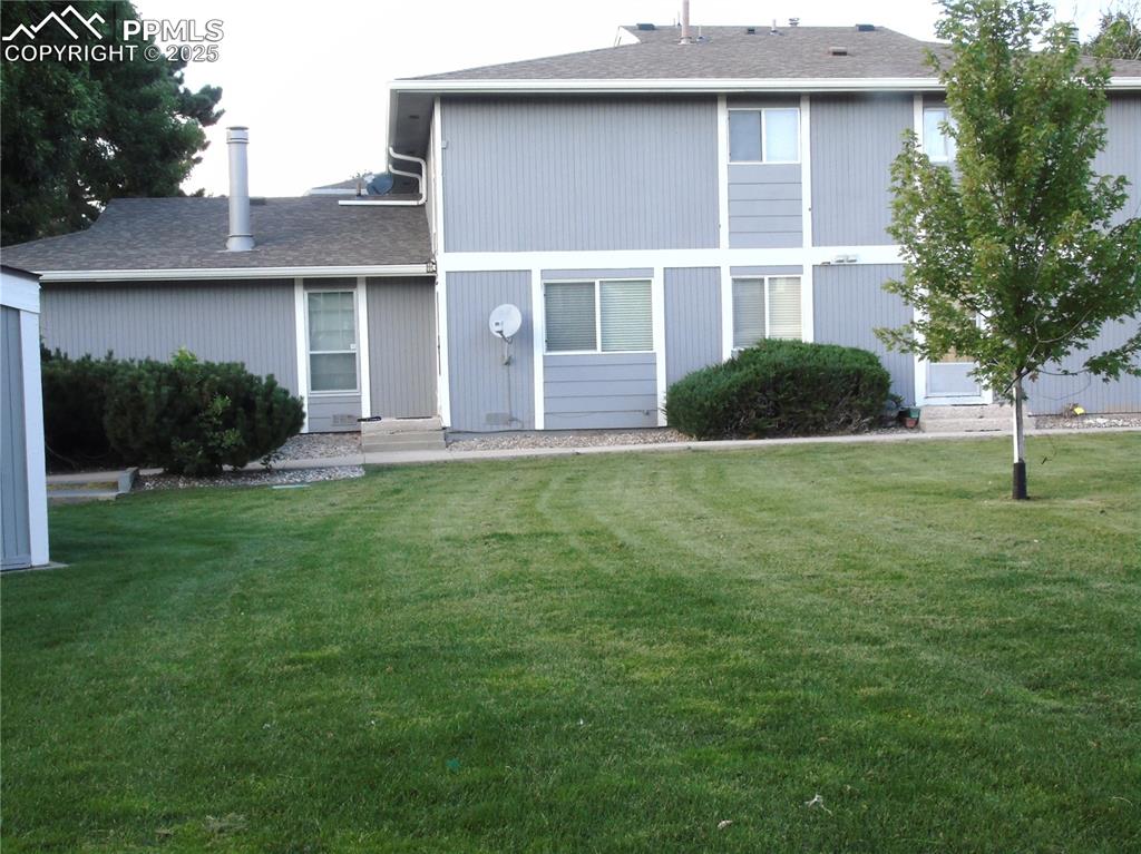 View of front of property with a shingled roof and a front lawn