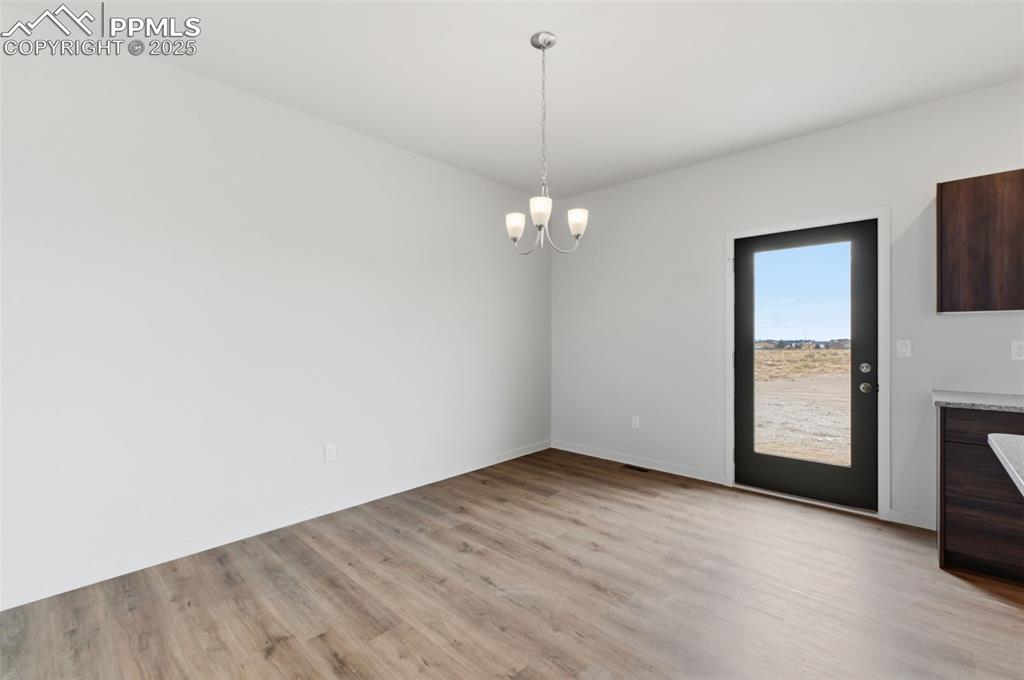Unfurnished dining area featuring a chandelier and light wood-style floors
