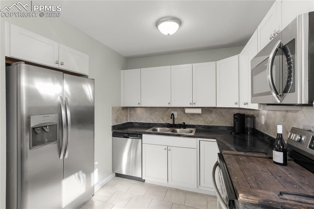 Kitchen featuring appliances with stainless steel finishes, backsplash, and white cabinetry