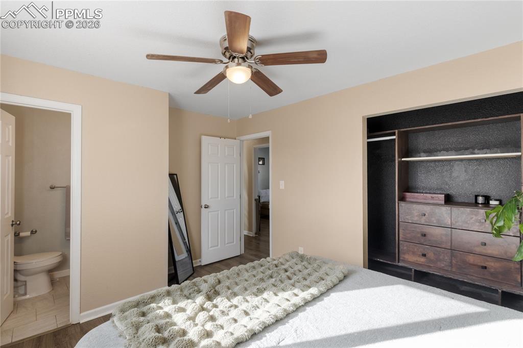 Bedroom featuring dark wood-style flooring, ceiling fan, a closet, and connected bathroom