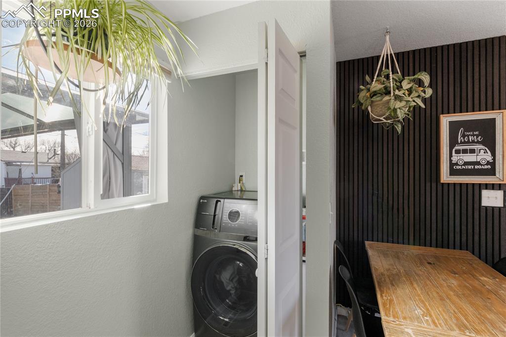 Laundry area with a textured wall and washer / dryer