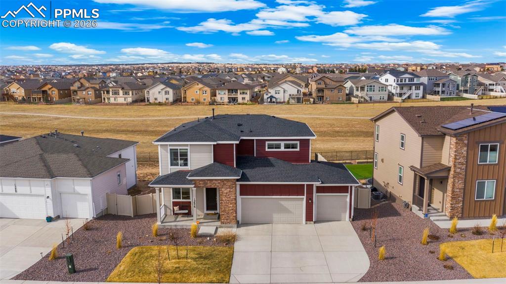 Traditional-style house featuring concrete driveway, roof with shingles, a residential view, and an attached garage