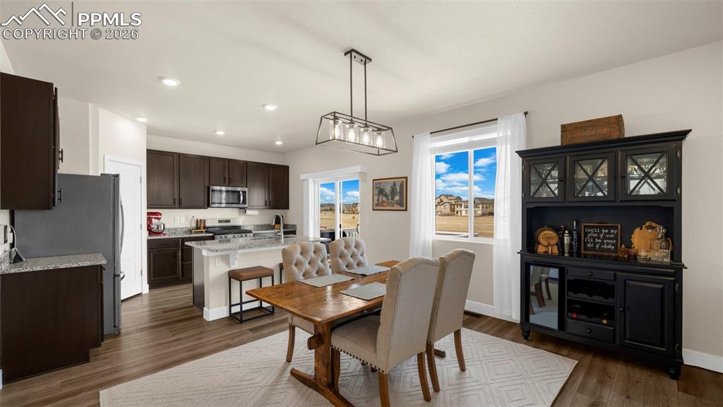 Dining room with dark wood-style flooring and recessed lighting
