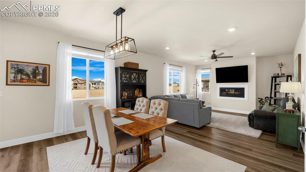 Dining space featuring wood finished floors, a glass covered fireplace, ceiling fan, and recessed lighting