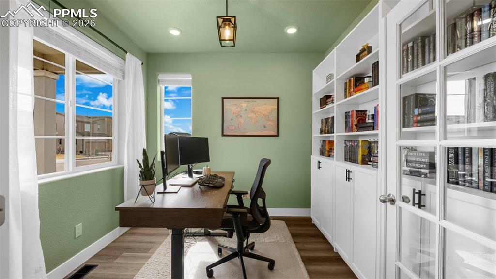 Home office with dark wood-style flooring and recessed lighting