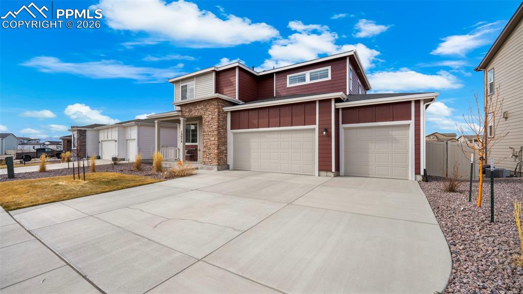 View of front of home with board and batten siding, driveway, a garage, and stone siding