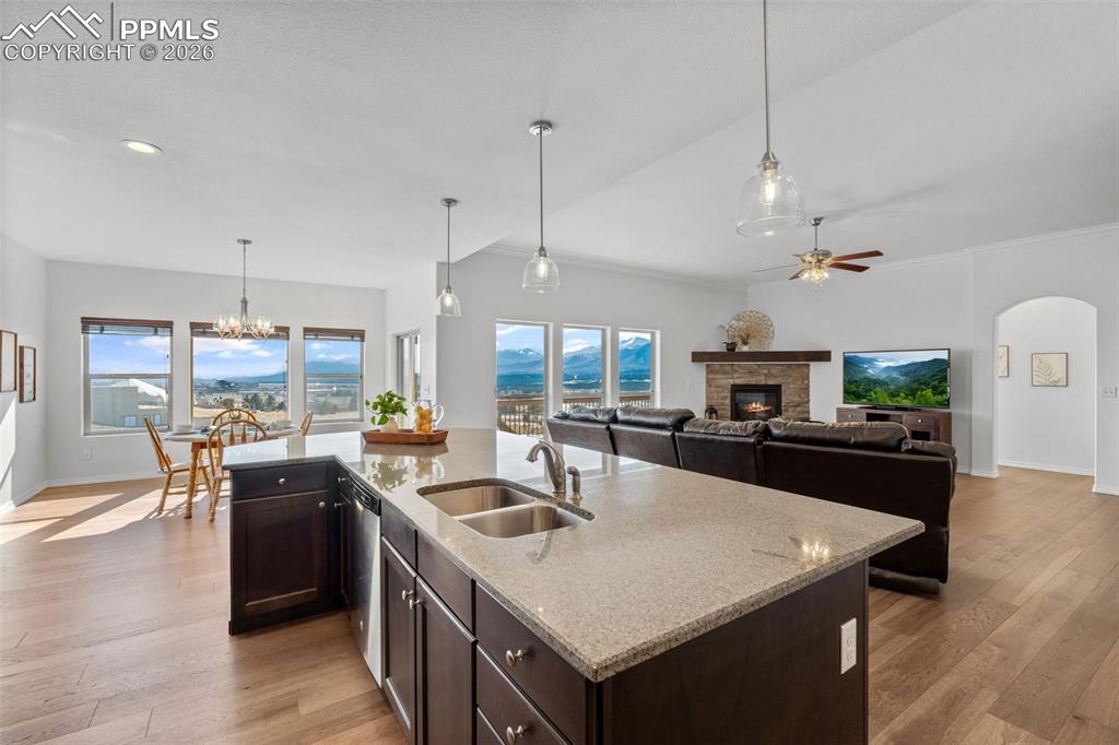 Kitchen with dark wood finish cabinetry, light wood finished floors, a glass covered fireplace, and light stone counters