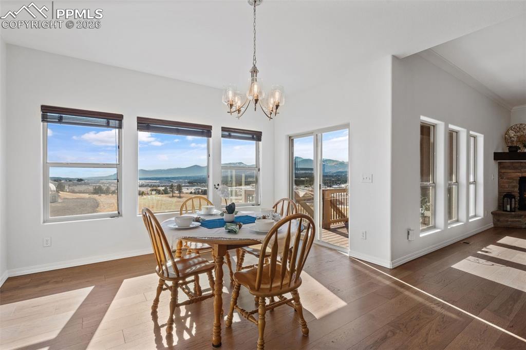 Dining space with a mountain view, a chandelier, a fireplace, crown molding, and wood-type flooring