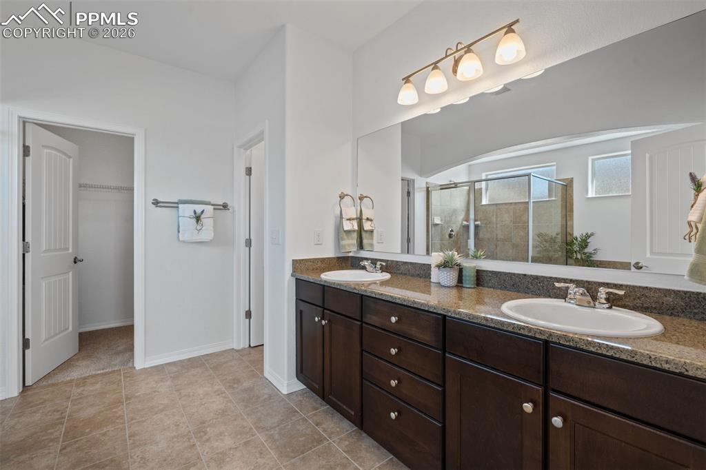 Bathroom with a stall shower, double vanity, and a walk in closet