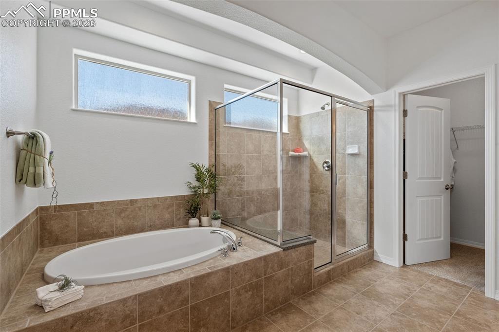 Full bathroom with a garden tub, a walk in closet, a shower stall, and tile patterned floors