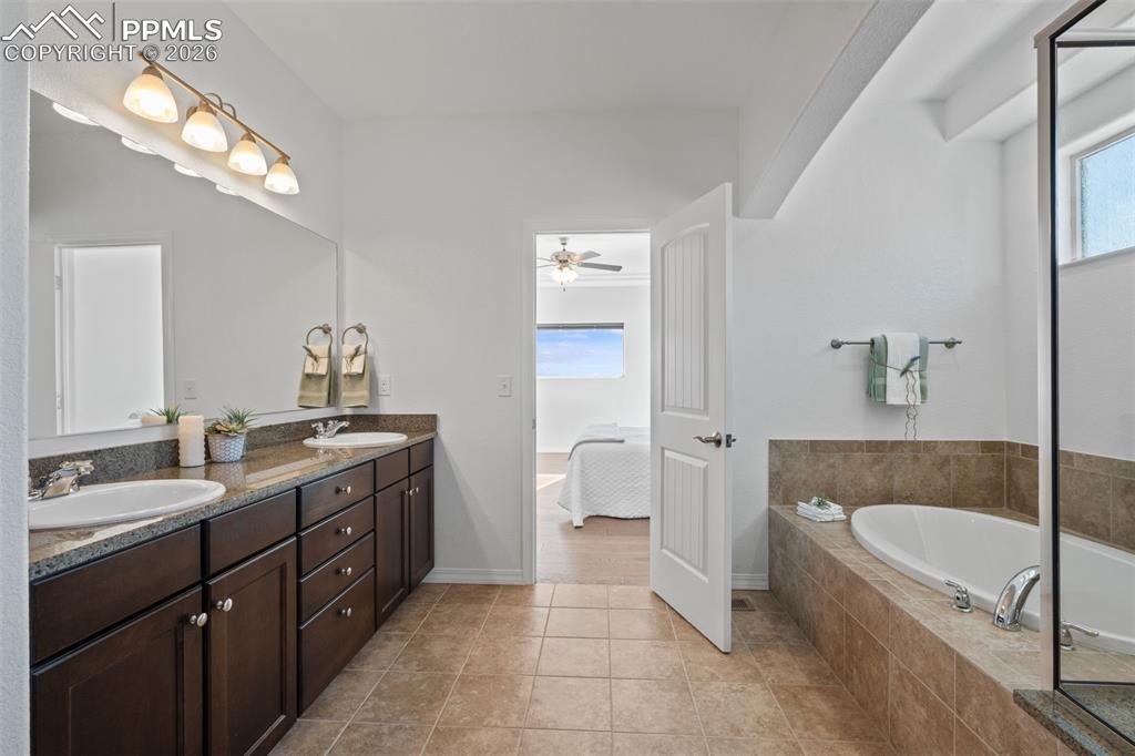Bathroom featuring double vanity, a garden tub, ensuite bath, and light tile patterned floors