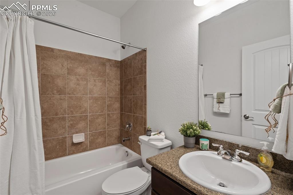 Full bath featuring shower / tub combo, vanity, and a textured wall