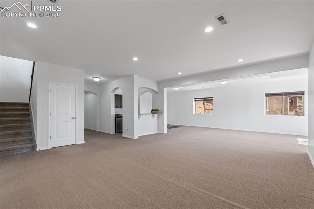 Unfurnished room featuring arched walkways, recessed lighting, and light colored carpet