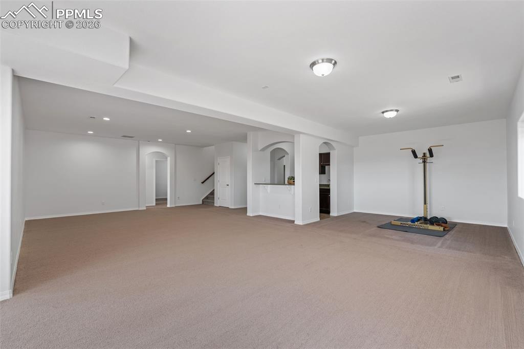 Below grade area with arched walkways and light colored carpet