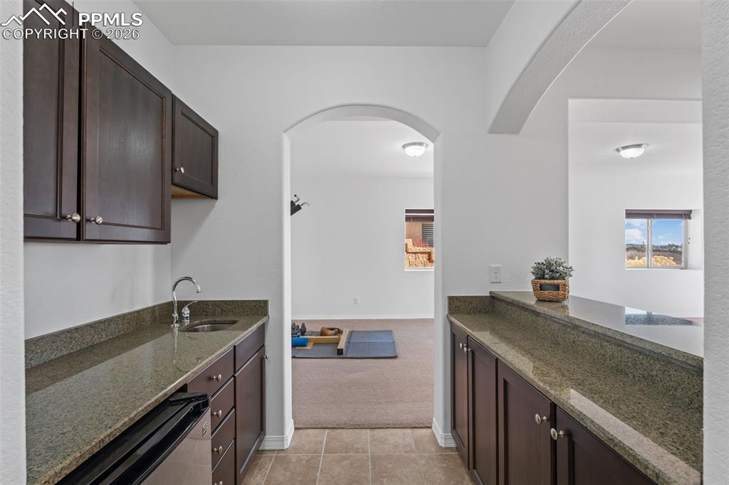 Kitchen with dark wood finish cabinetry, dark stone countertops, and arched walkways