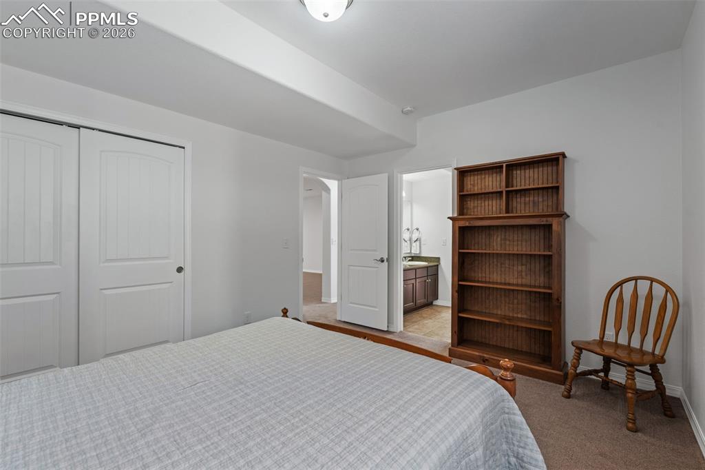 Bedroom with light colored carpet, ensuite bathroom, and a closet
