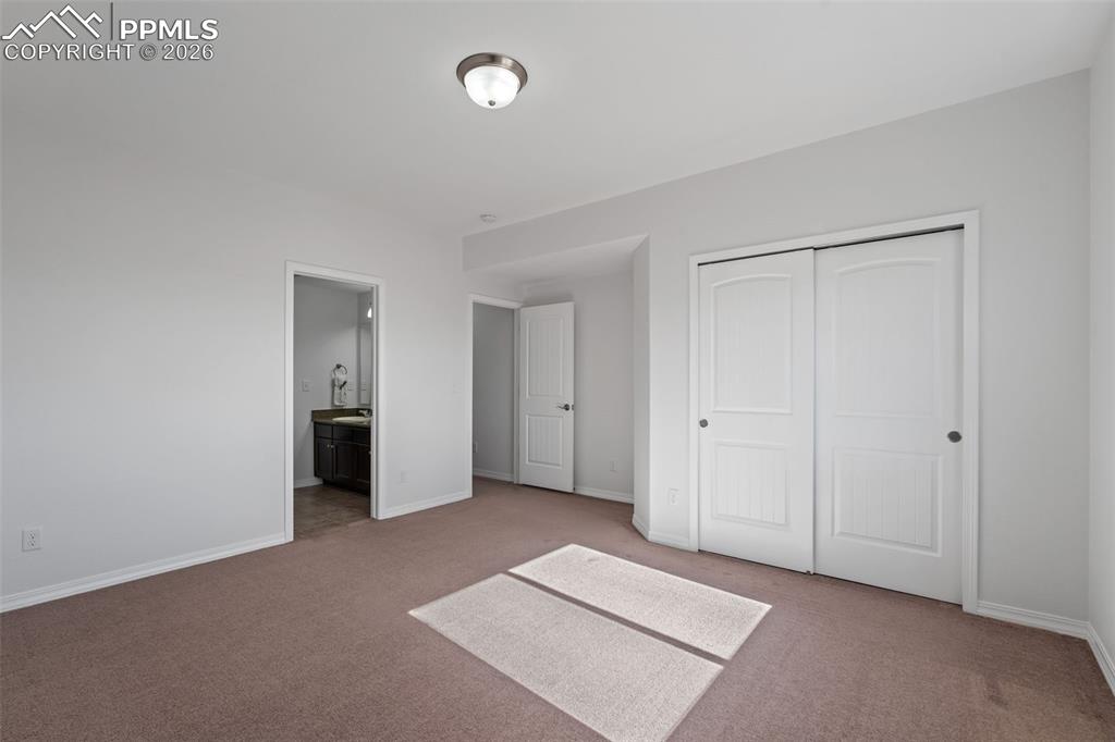 Unfurnished bedroom with carpet flooring, ensuite bath, and a closet