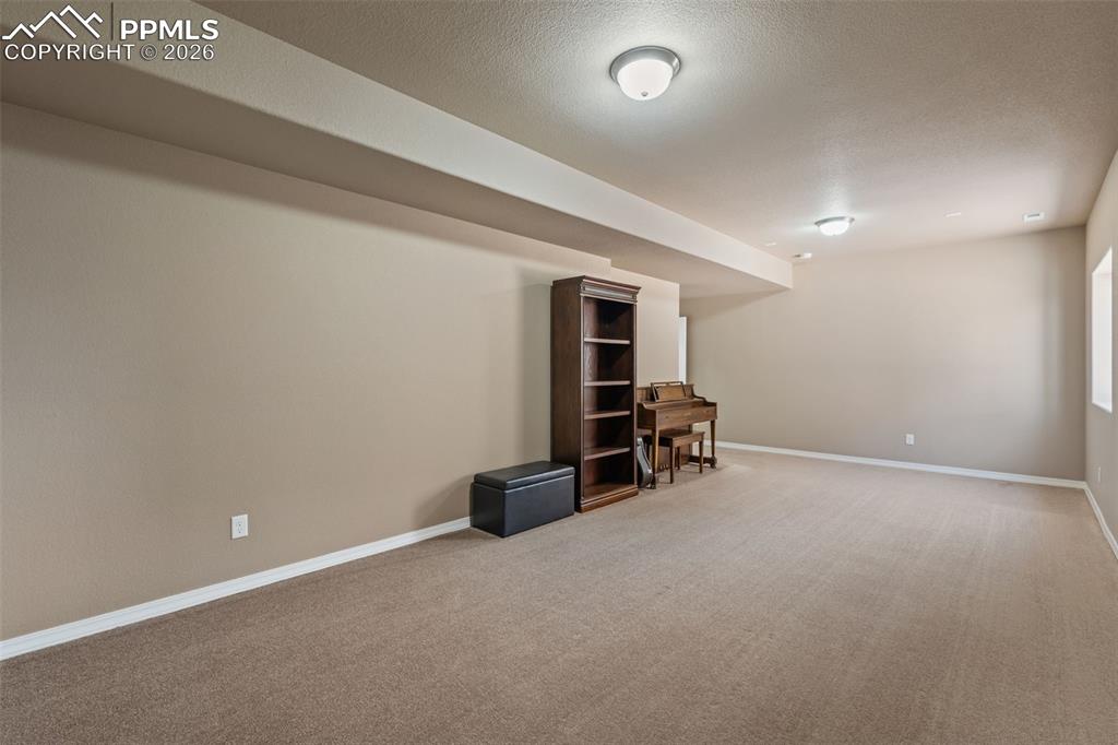 Finished basement with a textured ceiling and light colored carpet