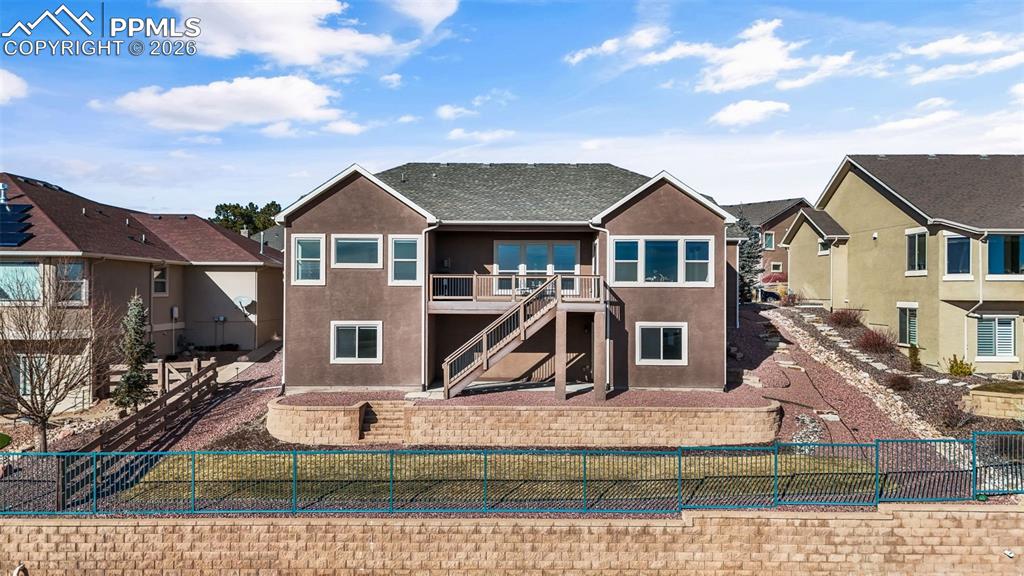 Rear view of property with a wooden deck, a fenced backyard, stucco siding, and a residential view