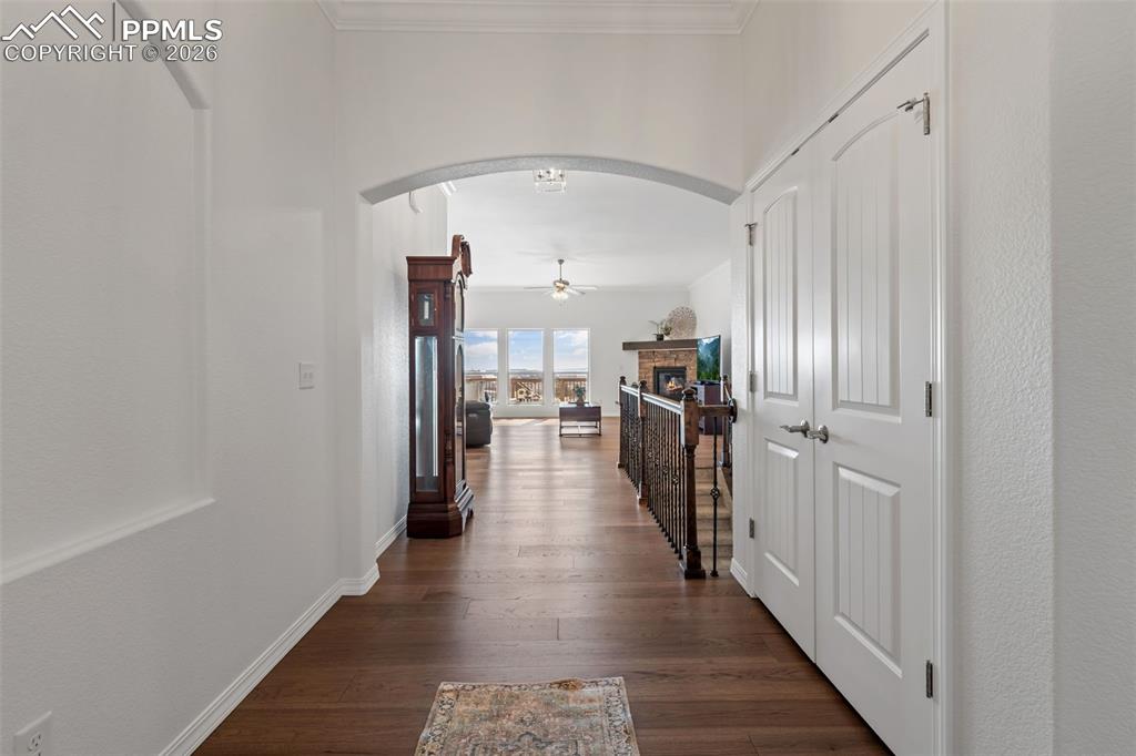 Corridor featuring arched walkways, dark wood-style floors, and ornamental molding