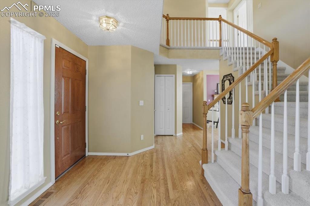Entry way with natural wood floors and sweeping stairs to the upper level.