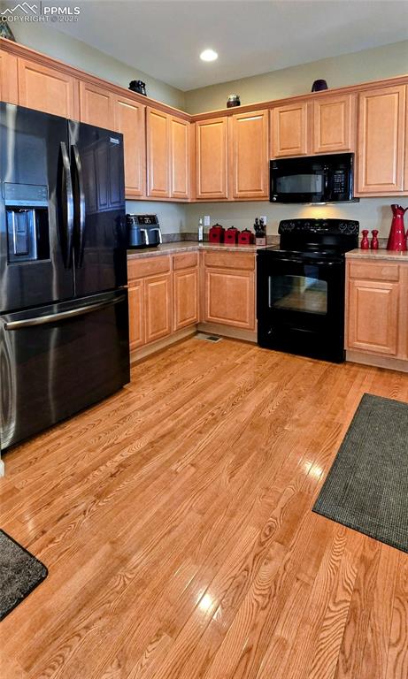 Kitchen featuring black appliances, light wood-style floors, and recessed lighting