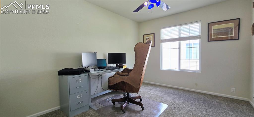 Carpeted home office featuring baseboards and ceiling fan
