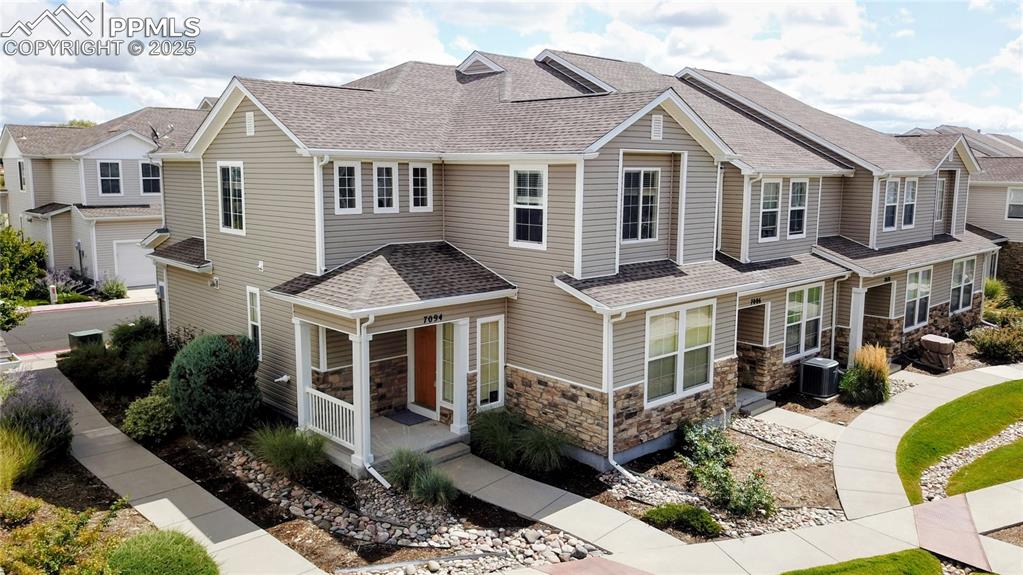 Craftsman inspired home featuring a shingled roof, stone siding, and a residential view