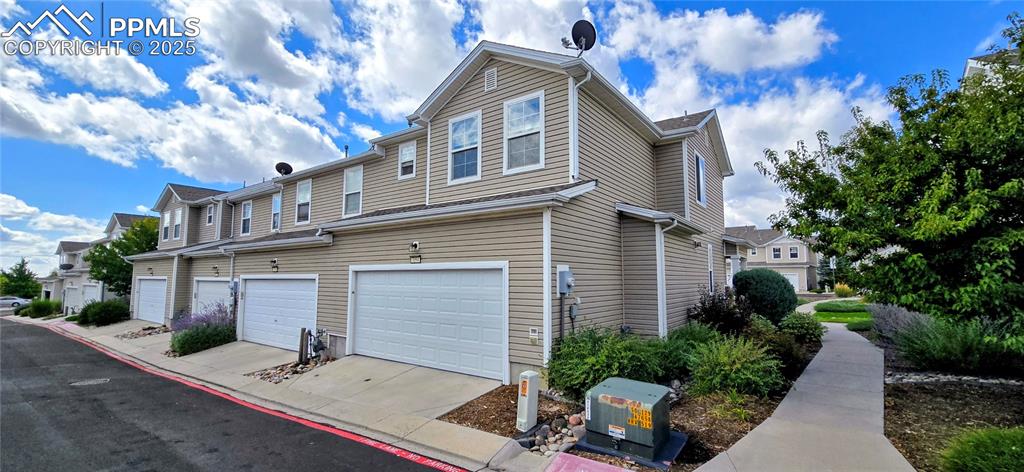 View of property exterior with a residential view, an attached garage, and driveway