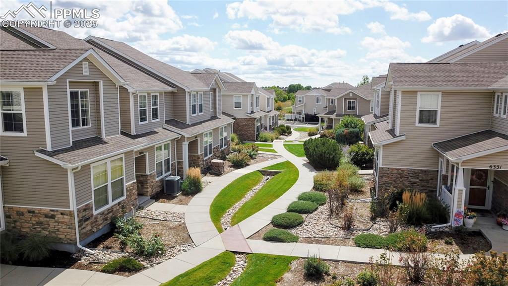 View of side of property with stone siding, a residential view, and a shingled roof